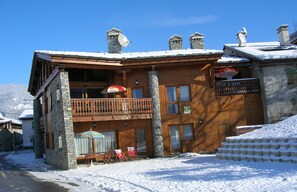 Un bâtiment en bois doté d’un balcon, une enseigne indiquant un restaurant, et une vue sur les montagnes.