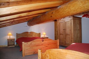 Un lit en bois orné d’une découpe en forme de cœur, deux lampes de chevet et une armoire en bois, le tout dans une pièce dont le plafond est en pente.