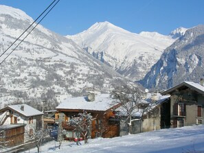 A snow-covered mountain village with traditional wooden houses, a clear sky, and a view of the surrounding peaks. - Apartment Les Soldanelles_ Chalet Darentasia (Bourg-Saint-Maurice)