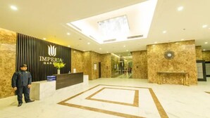 Un'hall d'hotel con una reception, un uomo in piedi e un grande motivo geometrico sul pavimento.