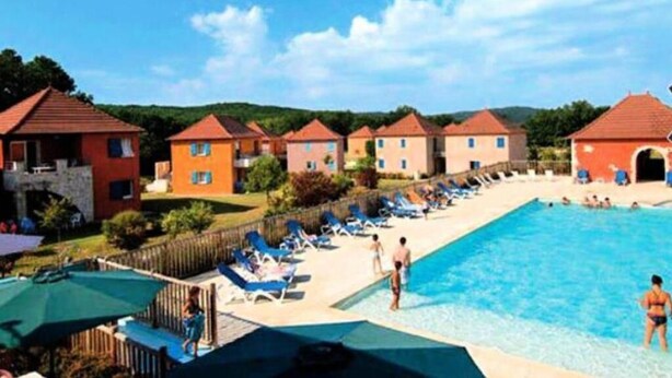 Un resort con piscina, tumbonas y villas.