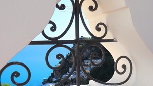 Ein Balkon mit schmiedeeisernen Geländern mit Blick auf ein Küstendorf mit weißen Häusern.