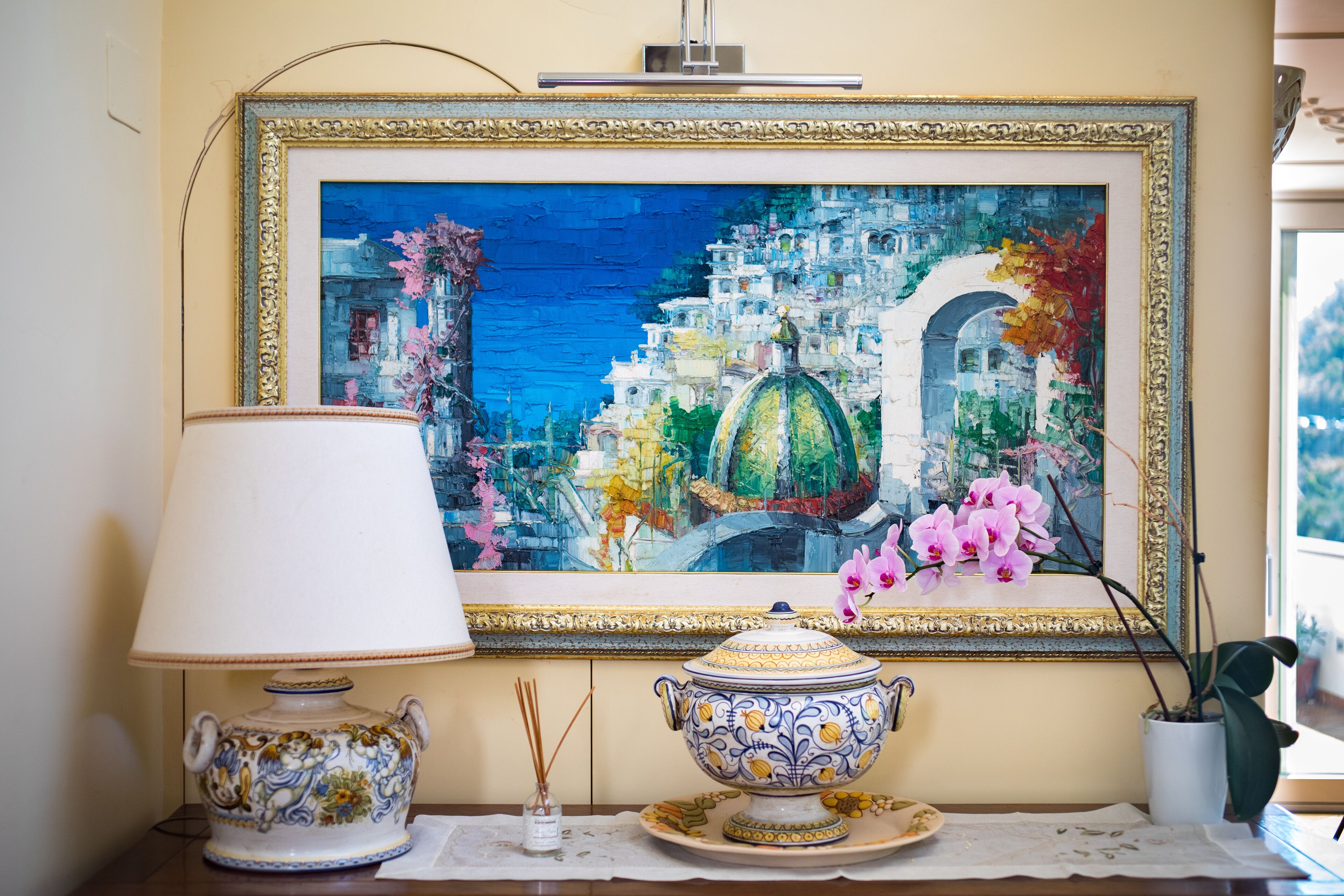 Une table avec une lampe, un bol décoratif et un vase rempli de fleurs.
