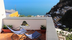 Eine Terrasse mit Meerblick, einem Stuhl und Kübelpflanzen.