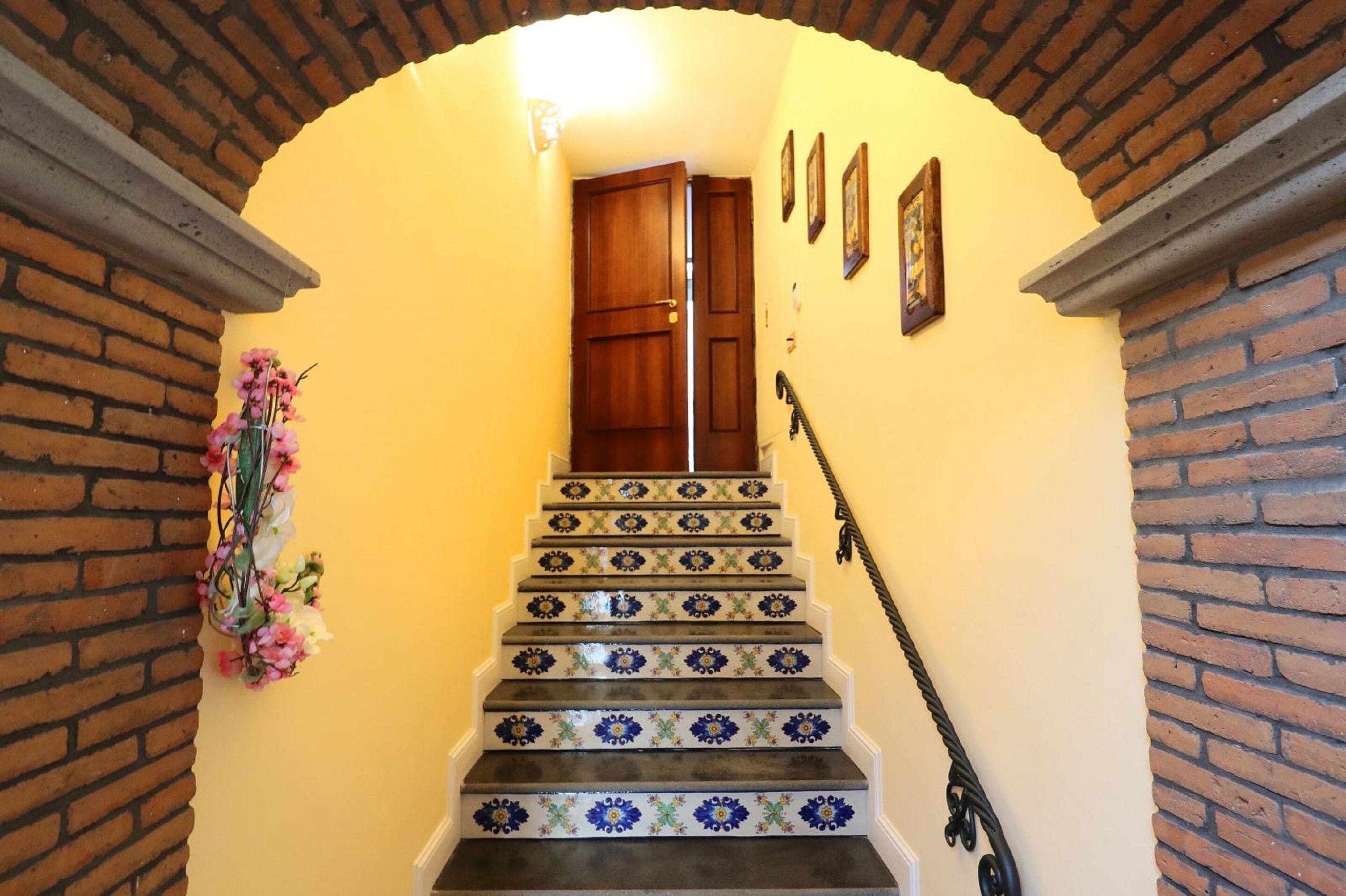A staircase with patterned tiles and a wooden door at the top.