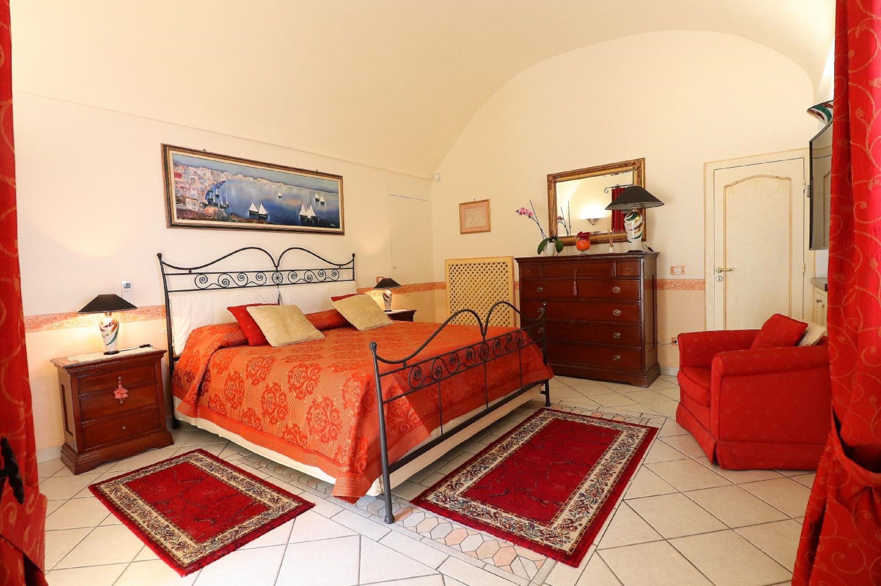 Ein Schlafzimmer mit Bett, Schminktisch, Nachttisch und roten Möbeln.