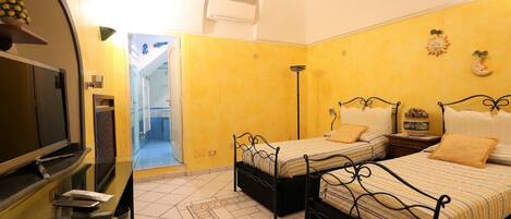 Une chambre d’hôtel avec deux lits, une télévision, une petite table et une salle de bain visible à travers une porte ouverte.