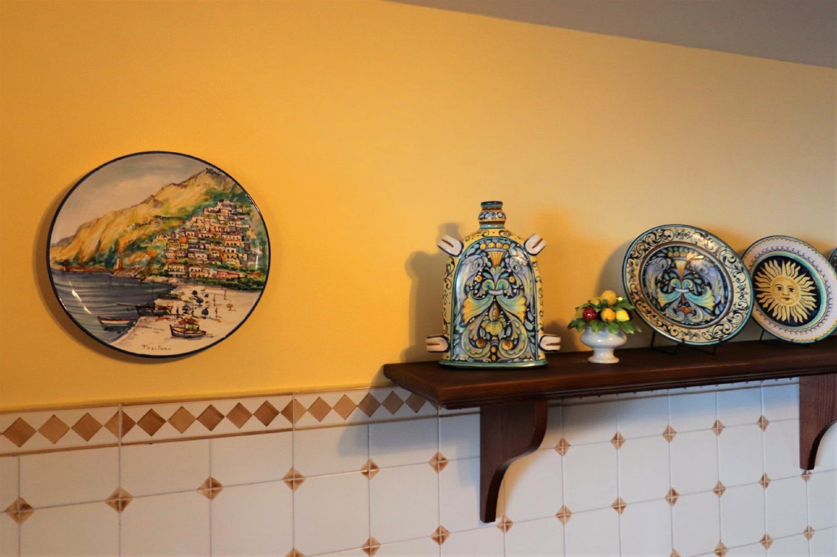 A wall with a coastal painting, ceramic vases, and decorative plates.