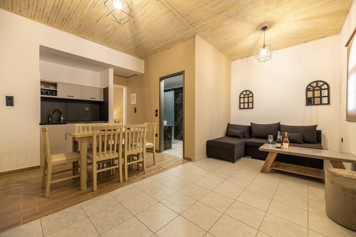 A modern living space with a dining area, a sofa, and a kitchen.