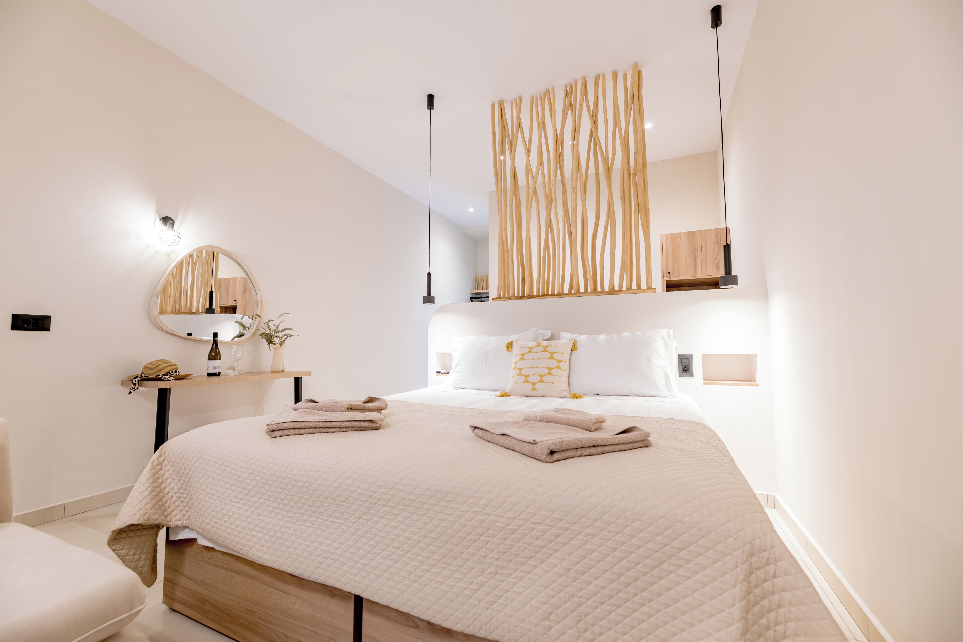 Un dormitorio moderno con una cama grande, mesitas de noche, un espejo y una lámpara colgante.