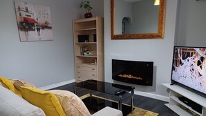 Una sala moderna con sofá, mesa de centro, televisor, estantería y obras de arte.