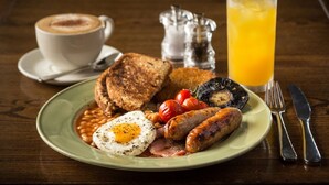 A plate of breakfast food including eggs, sausages, beans, tomatoes, and toast, with a glass of orange juice and a cup of coffee on the table. - The Grove Hotel (Haverfordwest)