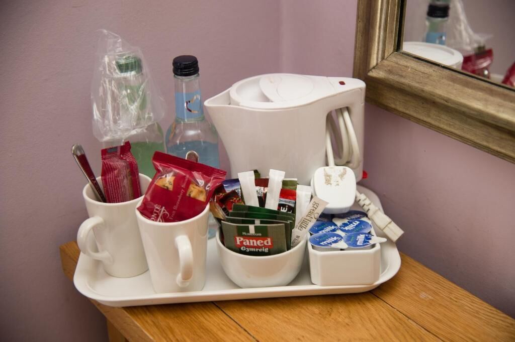 A tray with a coffee maker, a bottle, a mug, and a container with snacks.