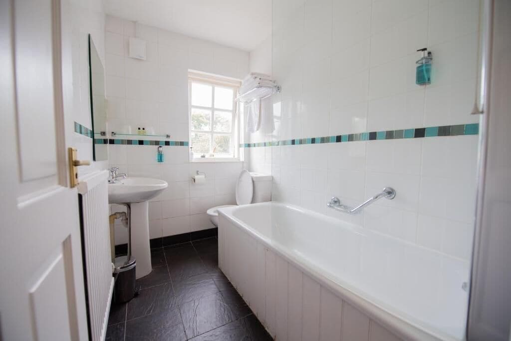 A bathroom with a bathtub, a sink, a toilet, and a window.