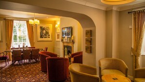 A hotel lobby with a fireplace, comfortable seating, and artwork on the walls. - The Grove Hotel (Haverfordwest)