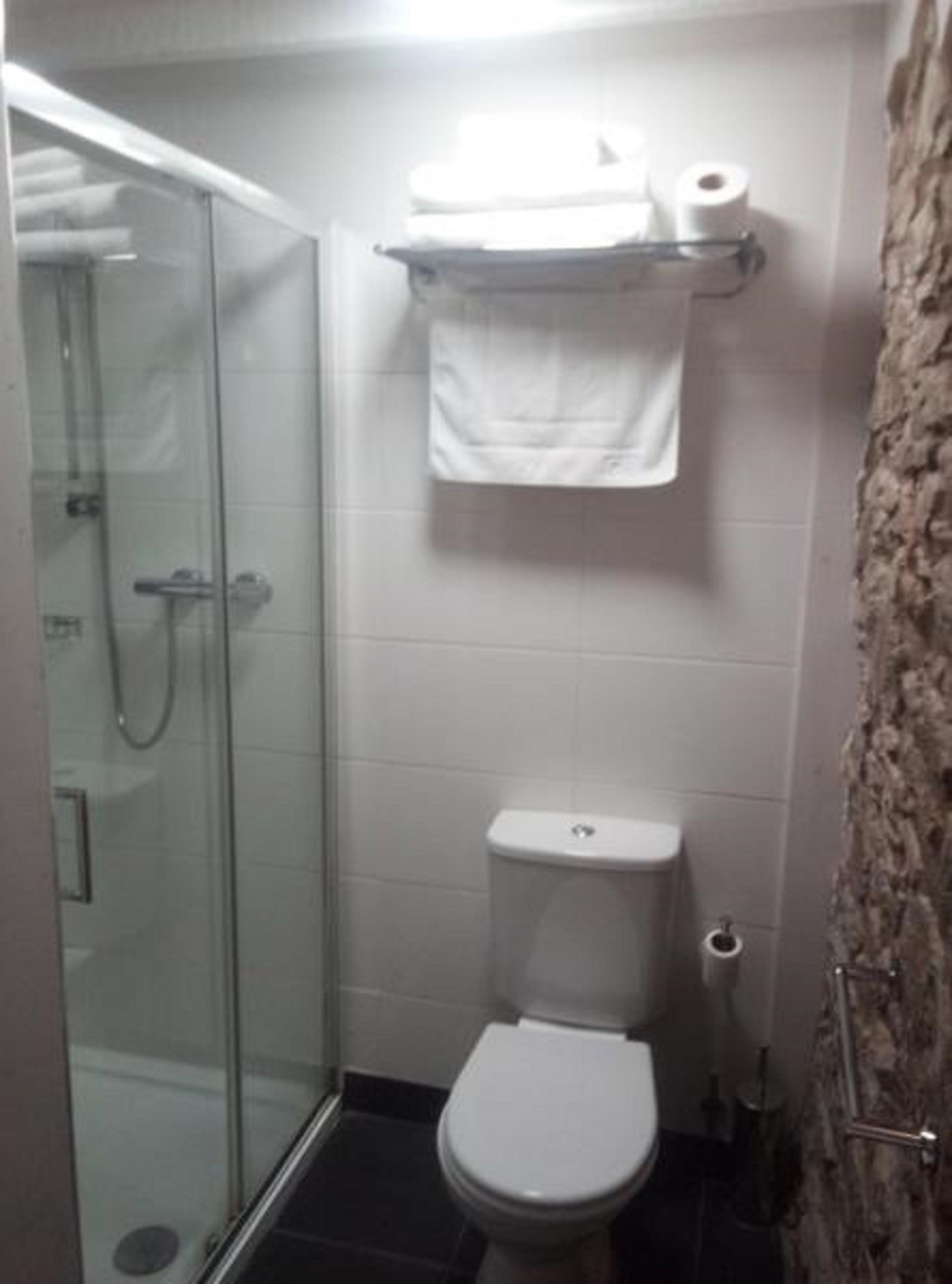 Ein Badezimmer mit einer Duschkabine, einer Toilette und einem Handtuchhalter mit Toilettenpapier.