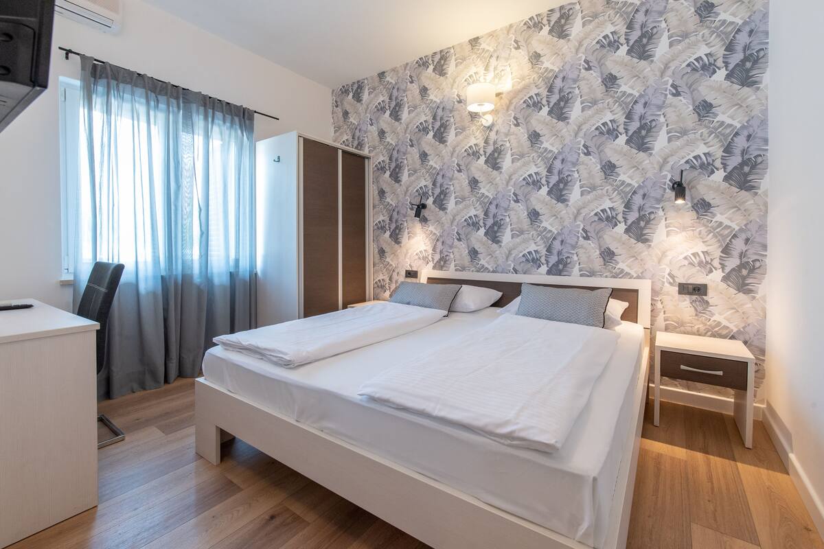 Un dormitorio moderno con una cama grande, un escritorio y un armario.