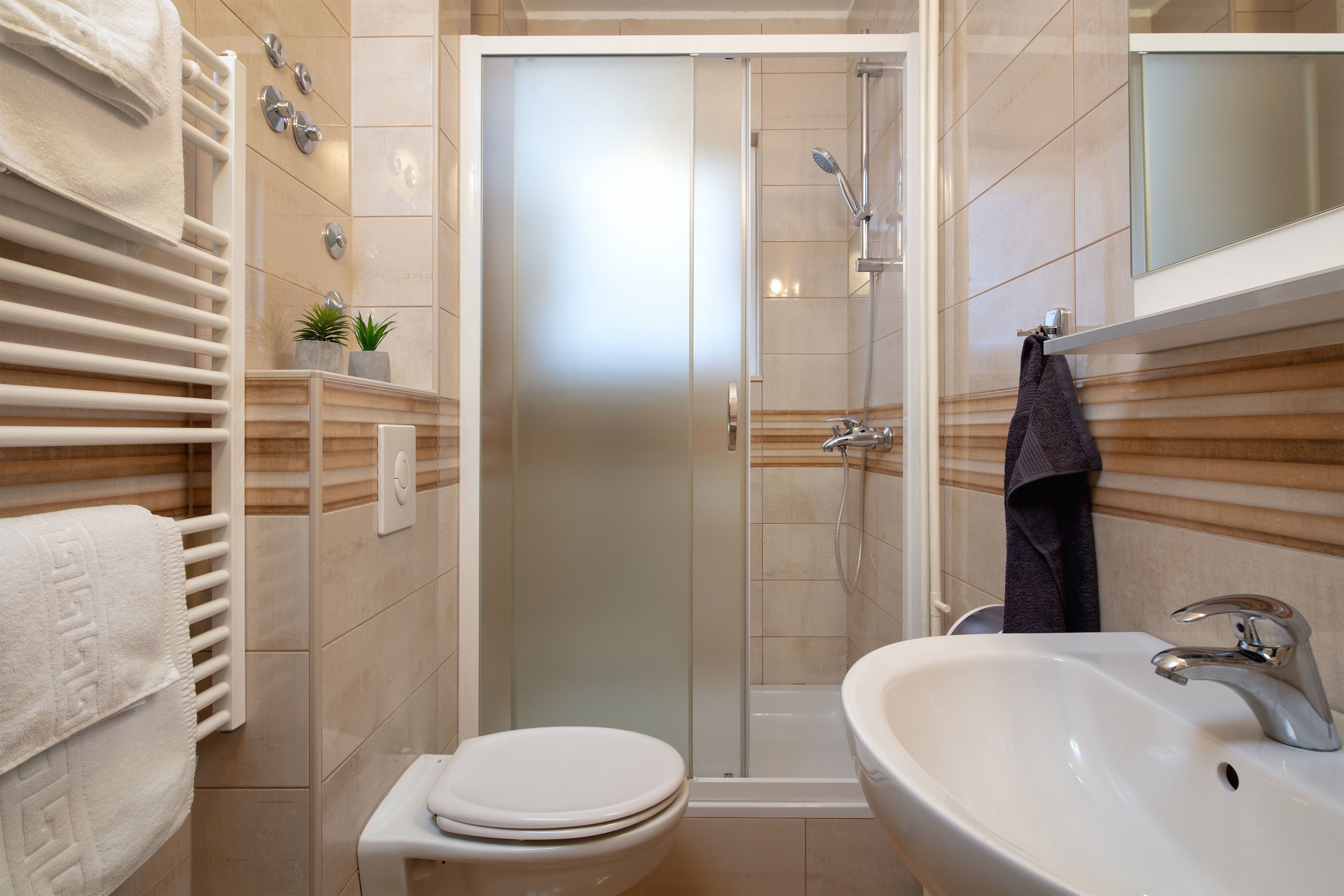 A bathroom with a toilet, sink, shower, and towel rack.