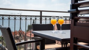 Un balcon avec deux verres de jus d’orange posés sur une table, donnant sur une étendue d’eau.
