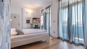 Une chambre moderne avec un lit, une télévision et un balcon agrémenté de rideaux.