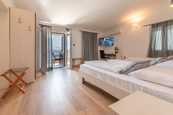 Une chambre d’hôtel moderne avec un grand lit, un bureau équipé d’un ordinateur et une télévision.