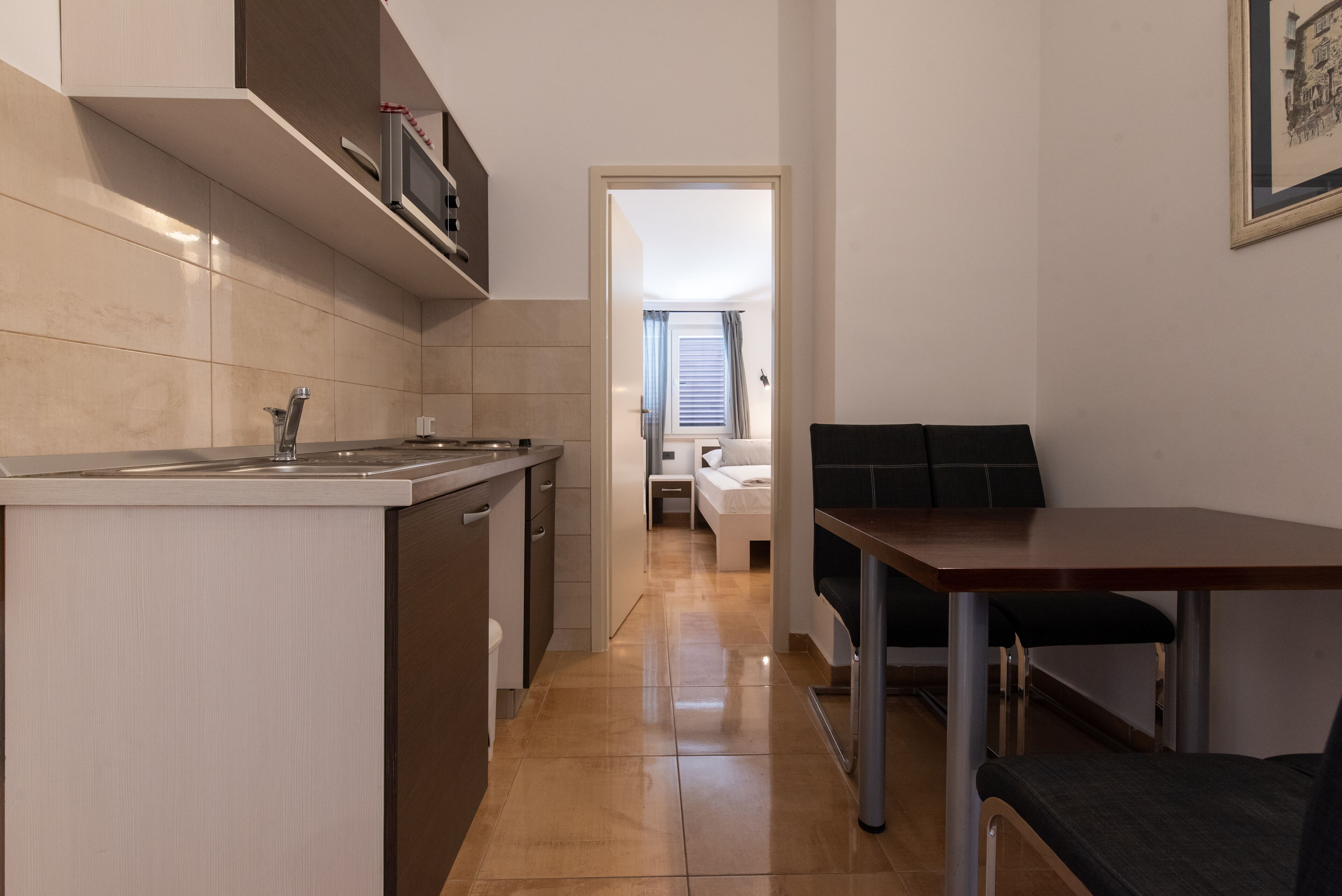 Una cocina compacta con zona de comedor, microondas integrado y una pequeña mesa con sillas.