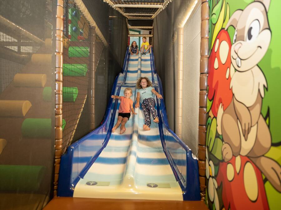 Eine Rutsche für Kinder mit Netzseiten und Wandmalerei mit Zeichentrickfiguren.