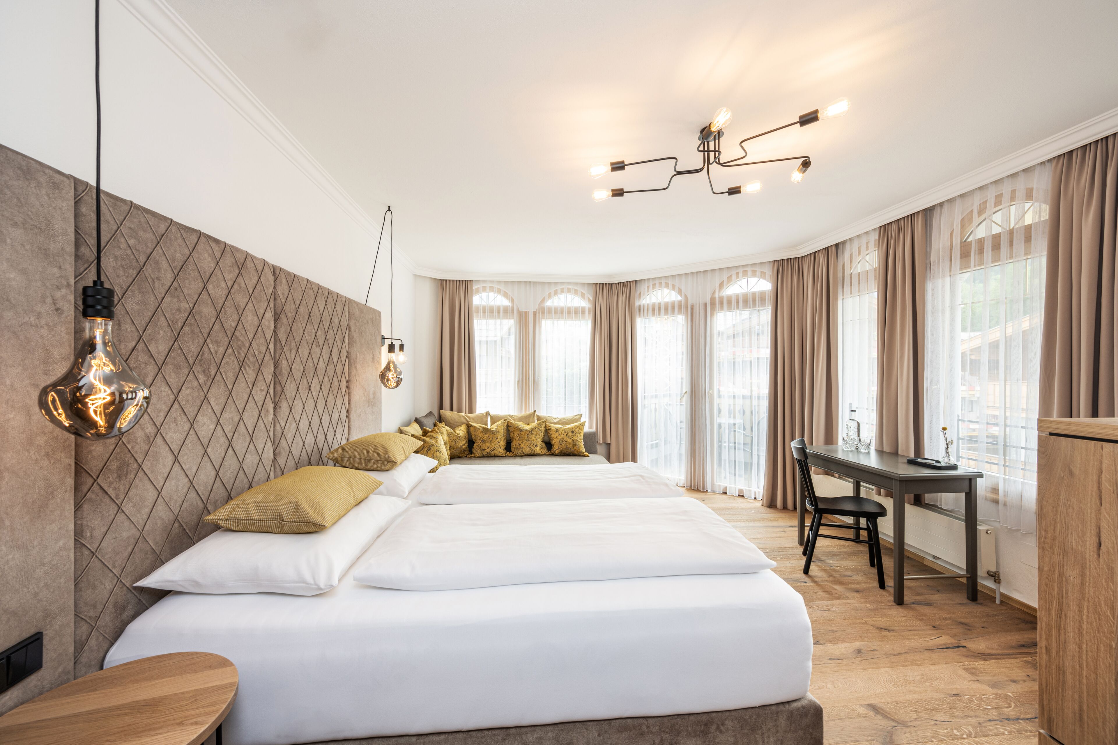 Una habitación de hotel moderna con una cama grande, un escritorio y una araña.