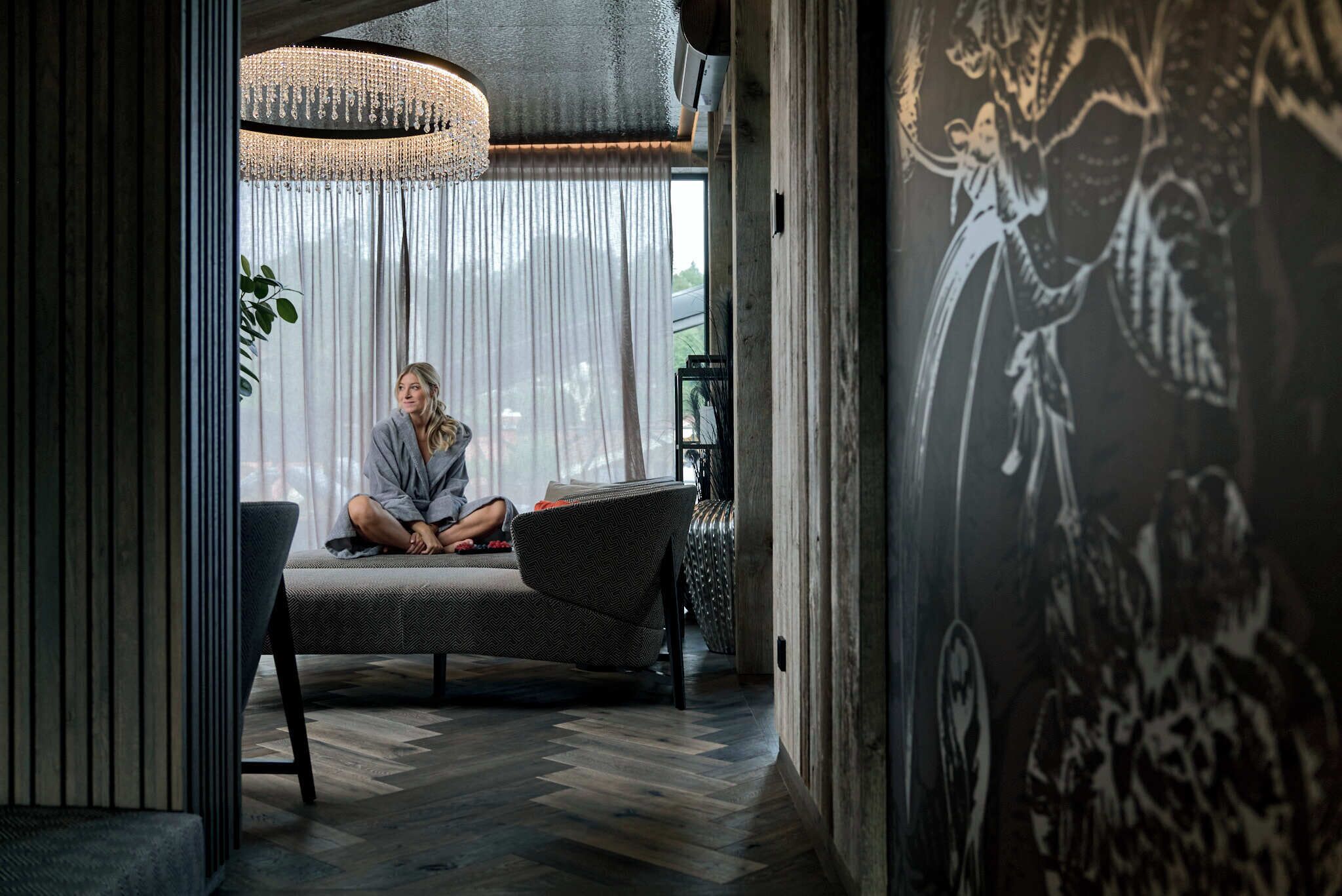 Een moderne woonkamer met een groot raam, een bank en een decoratieve wand.
