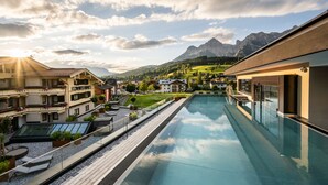 A swimming pool with a view of mountains and a town. - die Hochkönigin - Mountain Resort (Maria Alm am Steinernen Meer)