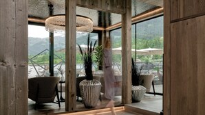 Un interior moderno con ventanas amplias, vigas de madera y un candelabro.