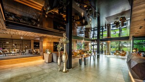 A spacious lobby with a high ceiling, modern furniture, and large windows offering a view of the outdoors. - die Hochkönigin - Mountain Resort (Maria Alm am Steinernen Meer)