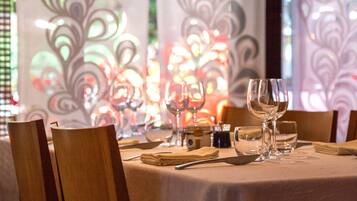 Una mesa de comedor preparada con sillas, una botella y copas de vino.