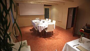 A conference room with a white table set for a meeting, a projector screen, and a door to the right.