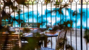Un comedor con vista a la piscina, con una mesa dispuesta con platos, vasos y cubiertos.