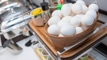 A basket of eggs on a wooden board in a kitchen setting.