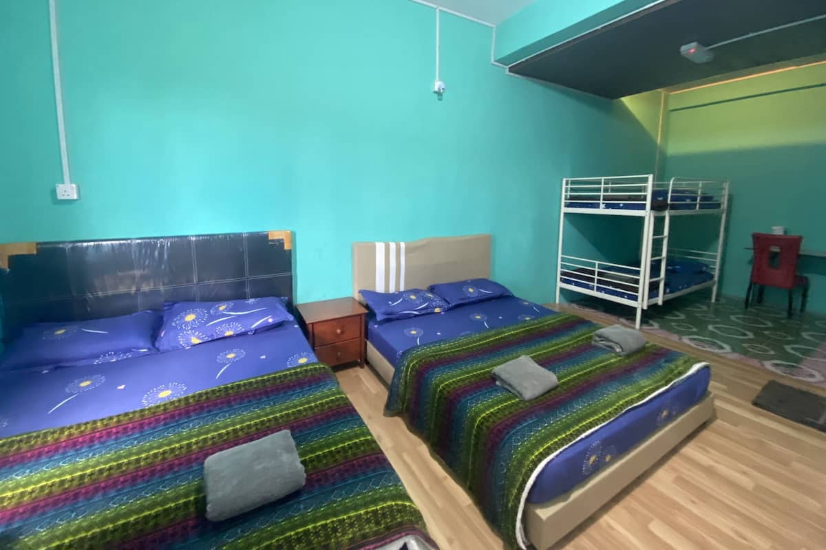 A room with two beds, a bunk bed, a small table, and a chair.