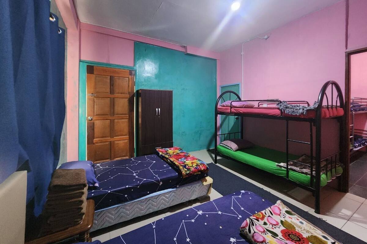 A dormitory room with bunk beds, a wardrobe, and a door.