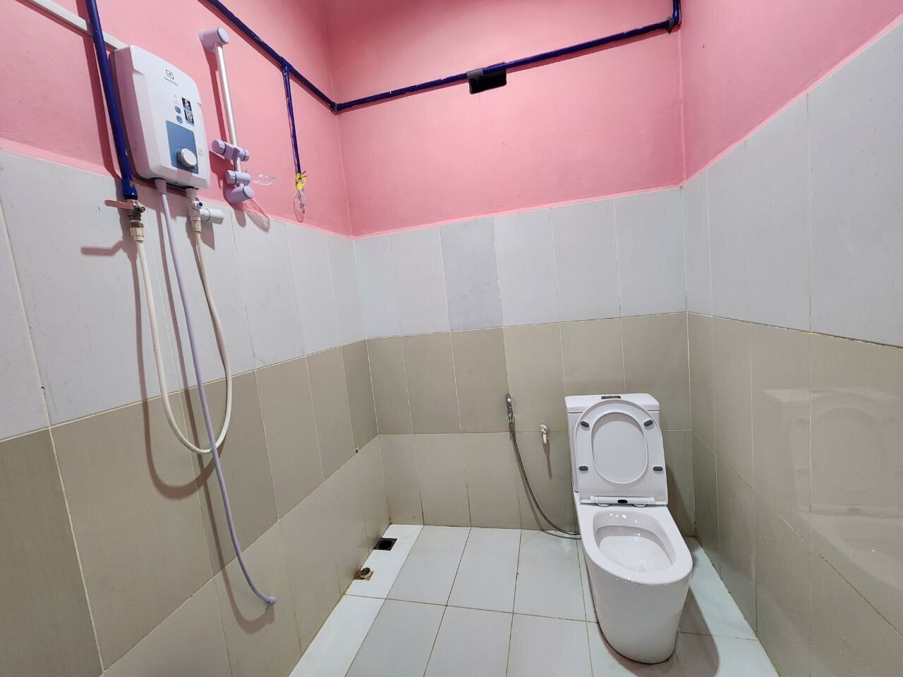 A small bathroom with a toilet, a shower, and a water heater.