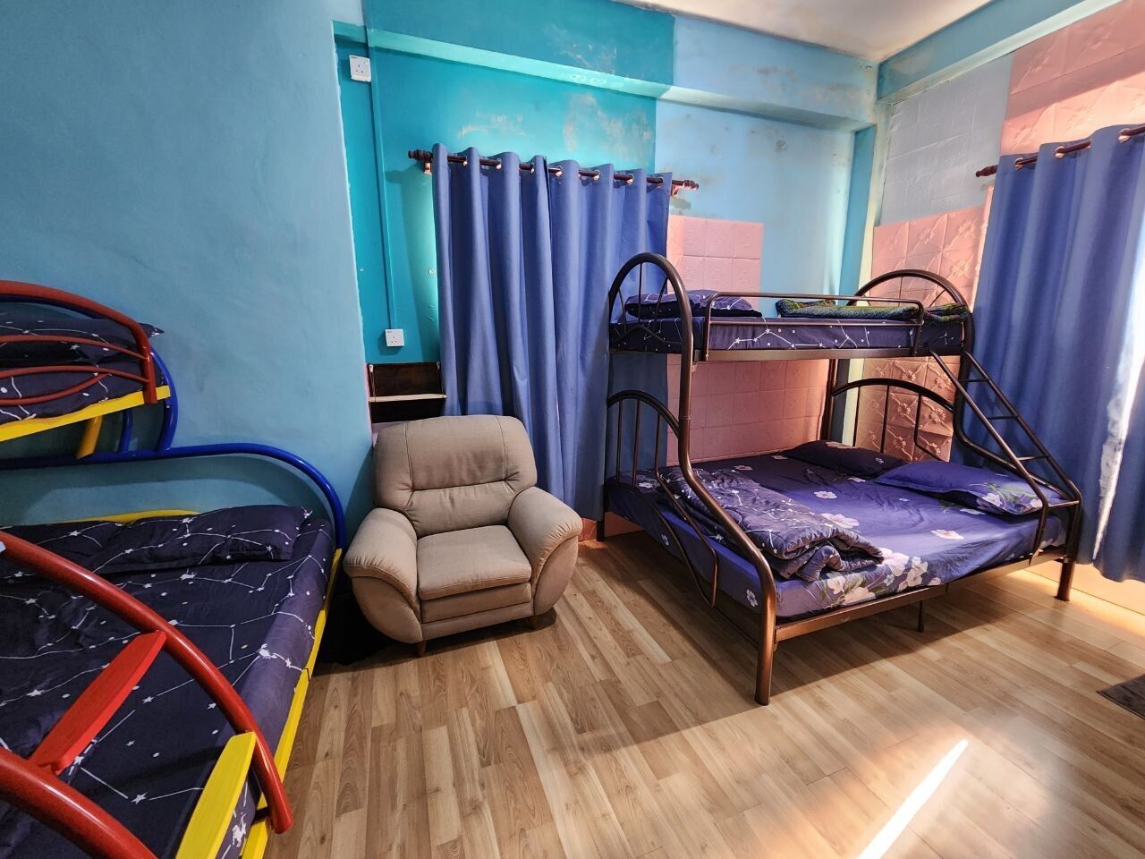 A room with bunk beds, a chair, and curtains.