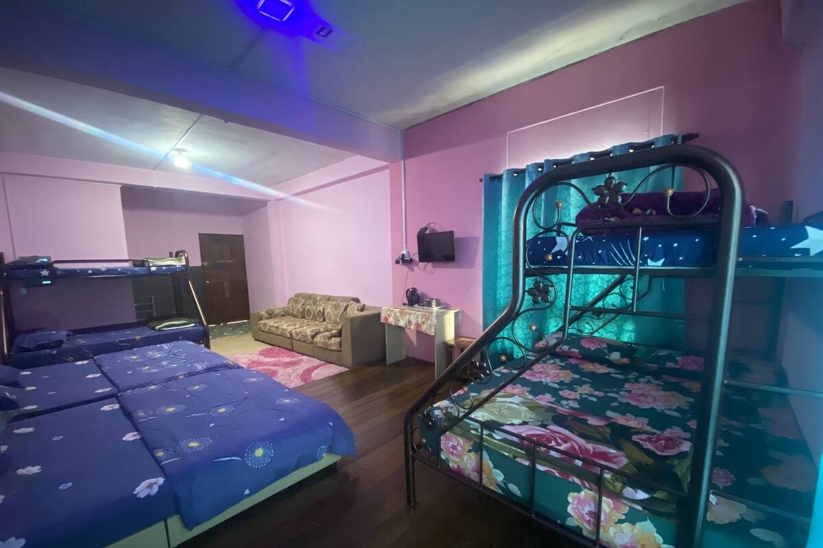 A bedroom with bunk beds, a sofa, a small table, and a TV.