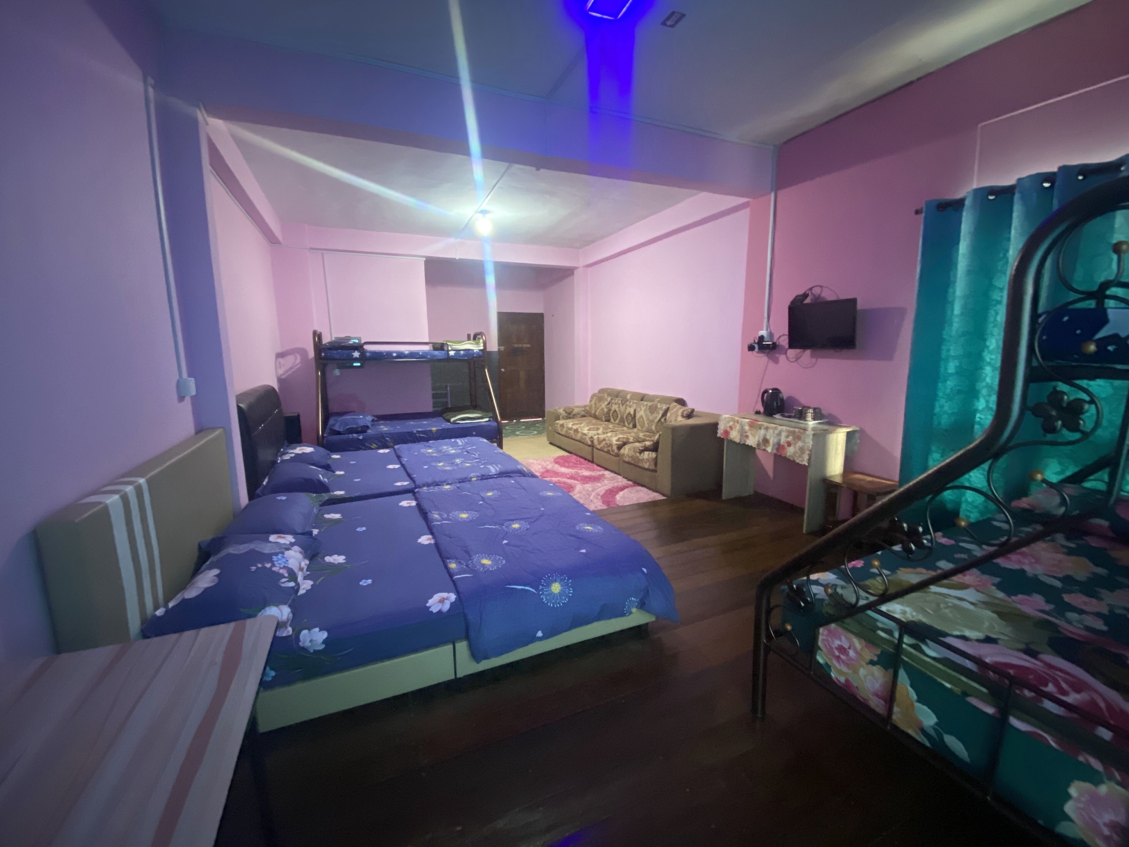 A room with bunk beds, a sofa, a small table, and a TV.