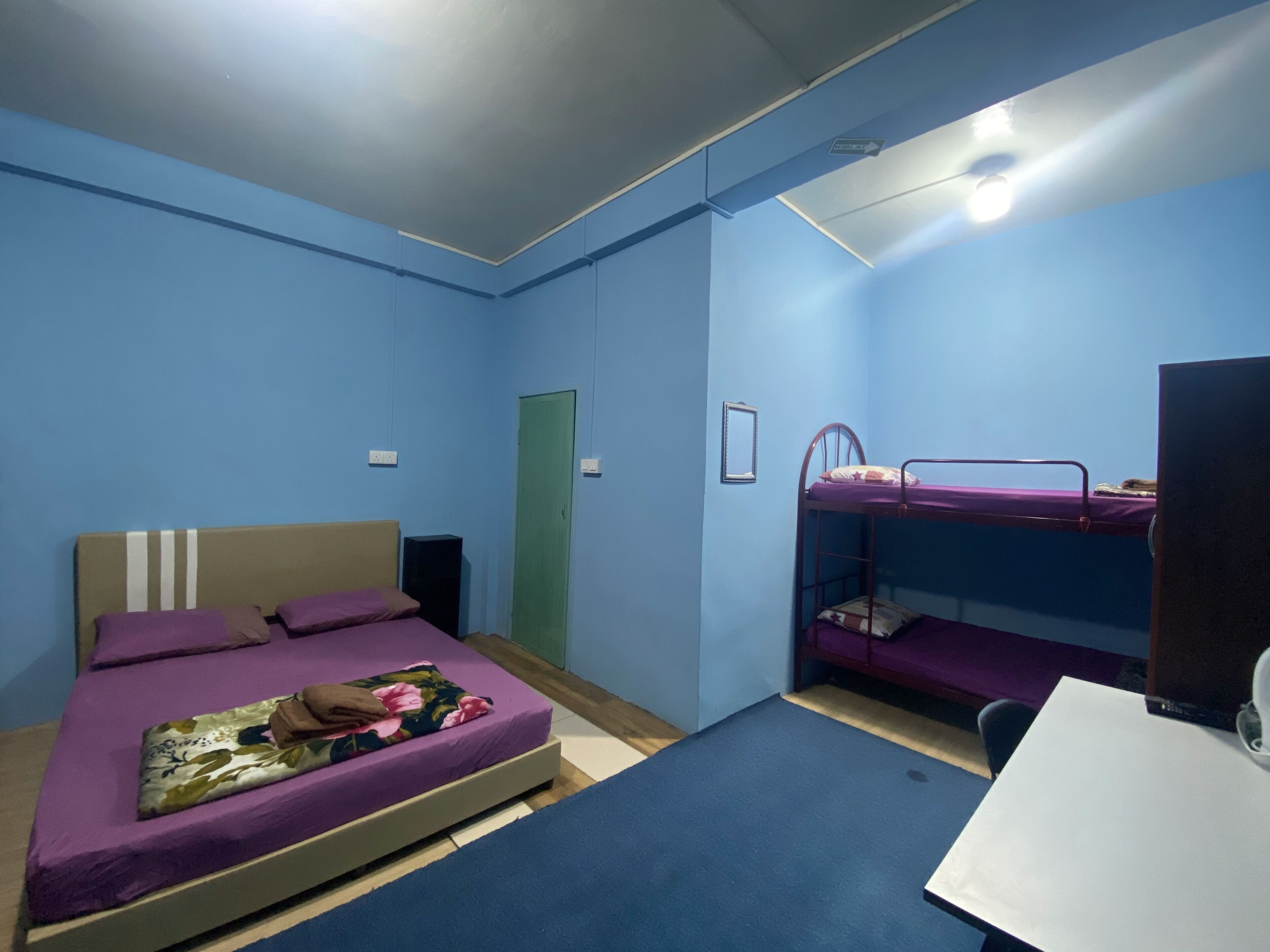 A room with a bed, a bunk bed, a desk, and a door.