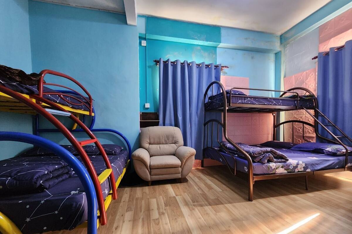 A room with bunk beds, a chair, and curtains.