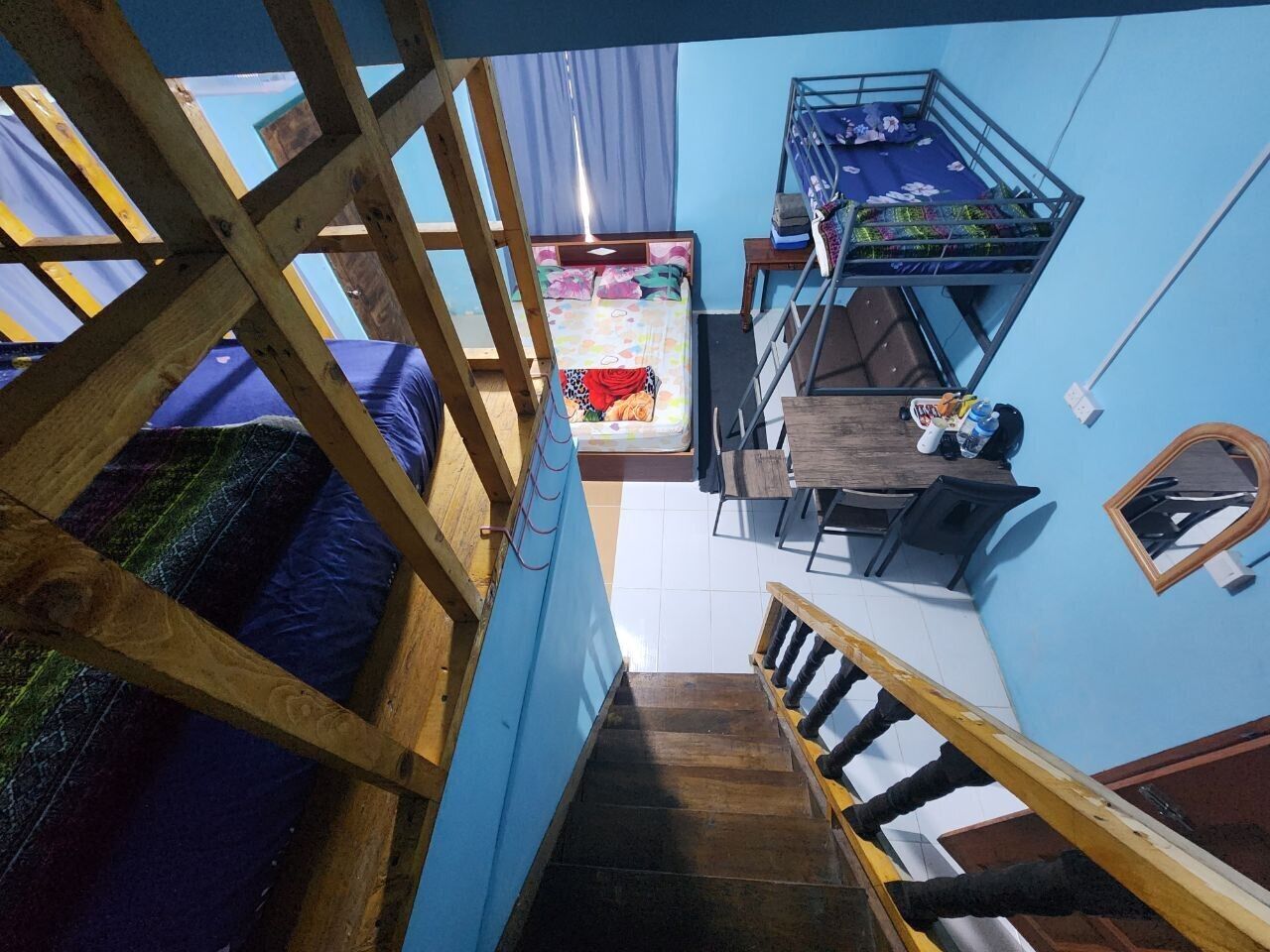 A dormitory-style room with bunk beds, a desk, and a chair.