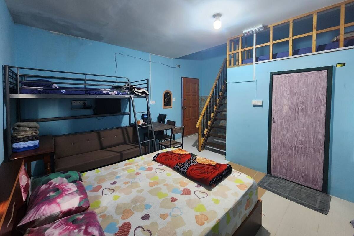 A dormitory room with bunk beds, a sofa, a desk, and a staircase.