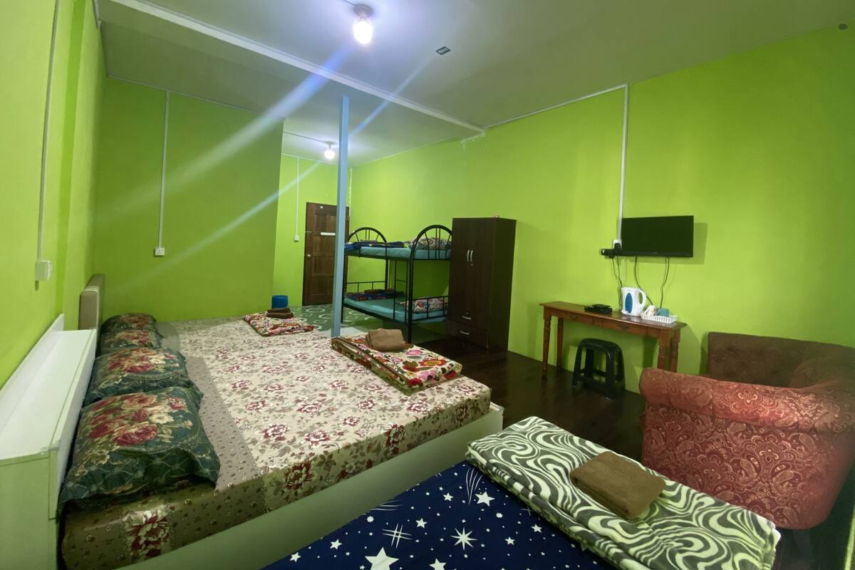 A room with a bunk bed, a desk, a chair, and a television.
