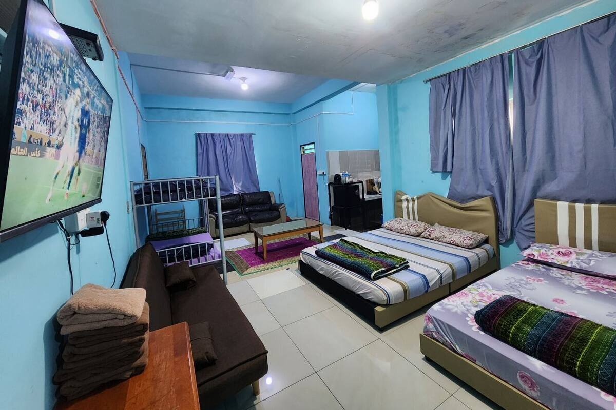 A room with two beds, a TV, a desk, and a chair.
