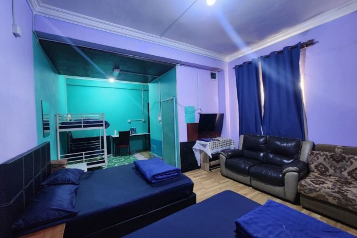 A room with bunk beds, a leather sofa, and a television.