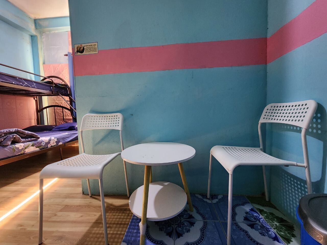 A small, brightly colored room with a bunk bed, two white chairs, and a small round table.